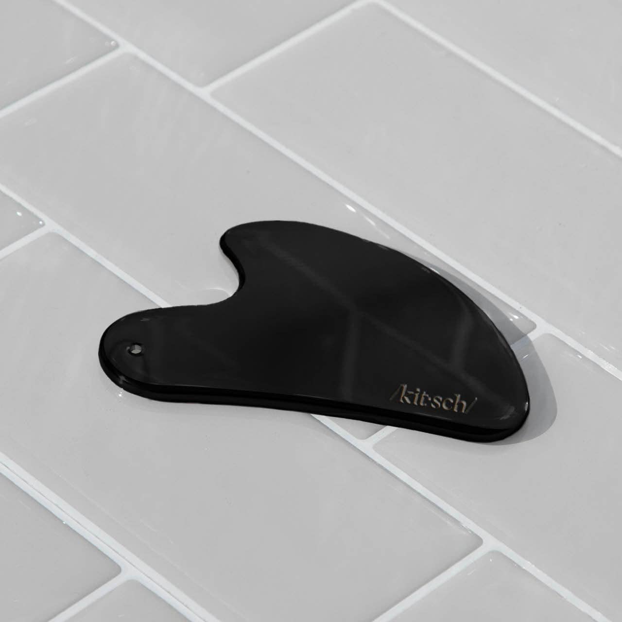 KITSCH stainless steel Gua Sha tool in matte black, designed for facial massage and skin contouring.